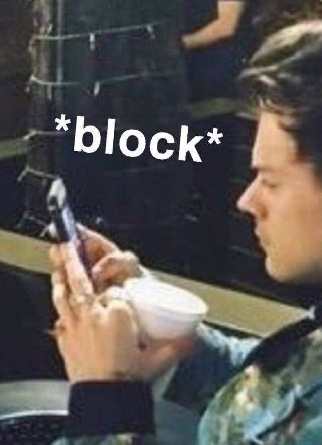 a man sitting in a car looking at his cell phone with the word block on it