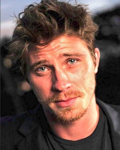 a close up of a person wearing a black shirt and looking at the camera with a serious look on his face