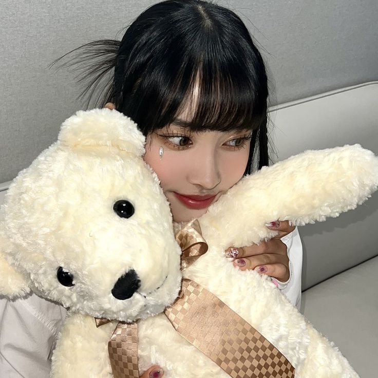 a woman is holding a white teddy bear