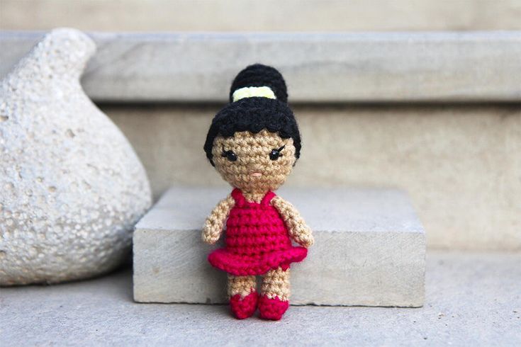 a crocheted doll sitting on top of a cement block