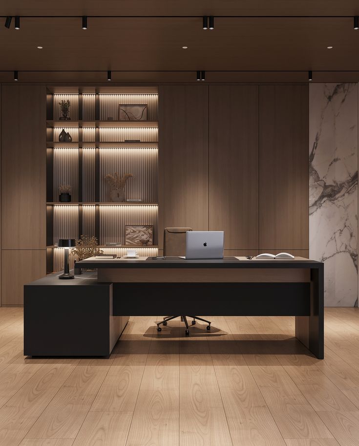 an office desk with a laptop on it in front of a bookcase and shelves