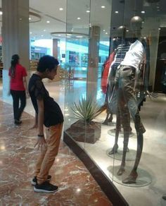 a woman standing in front of a glass display case filled with mannequins