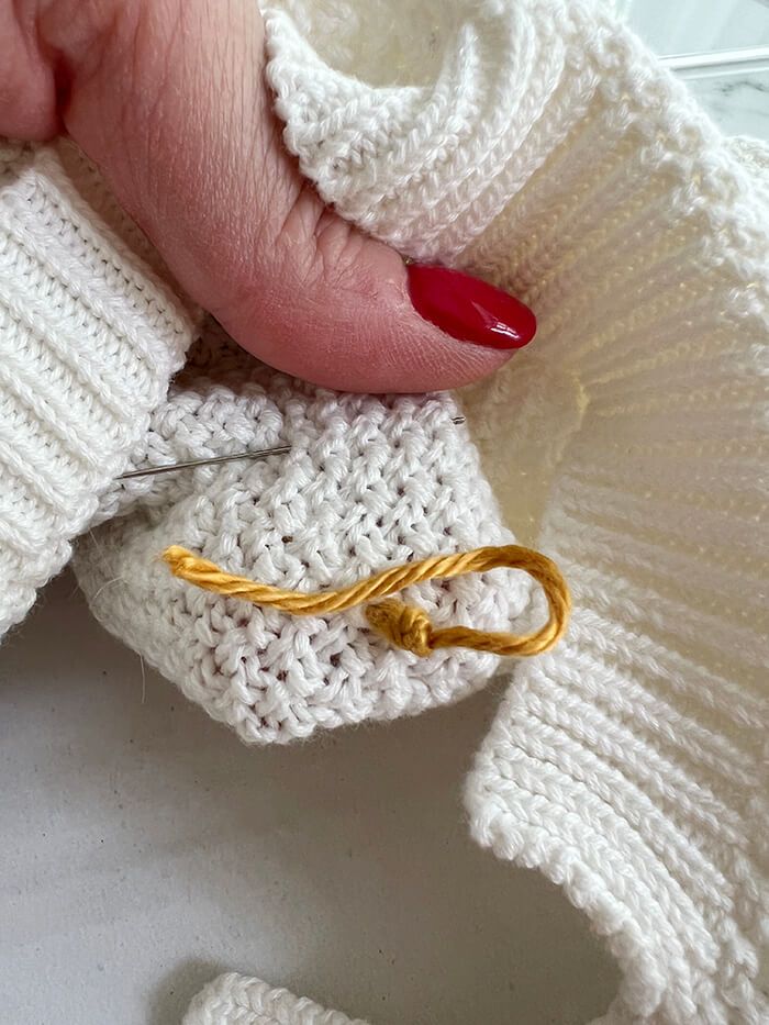 a woman's hand holding onto a knitted sweater with a gold ring on it