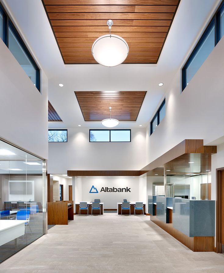 the inside of an office building with glass walls and wood ceilinging, along with tables and chairs