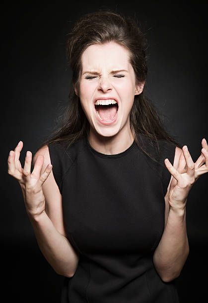 a woman with her mouth wide open and hands in the air, making an angry face