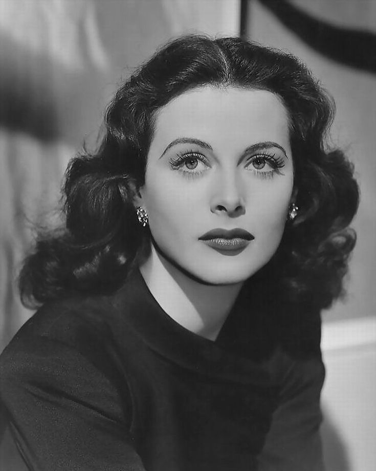 an old black and white photo of a woman with dark hair, wearing large earrings