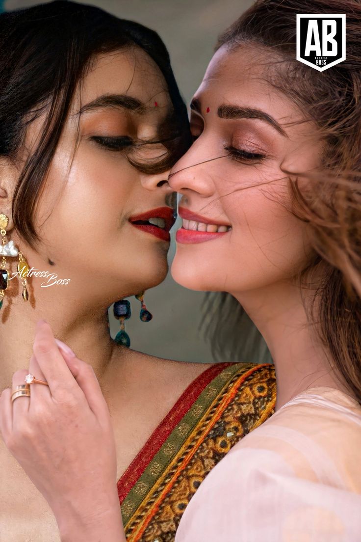 two women are kissing each other with their eyes closed and one is wearing gold earrings