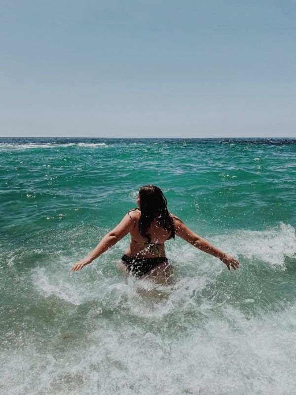 a woman standing in the ocean with her arms outstretched