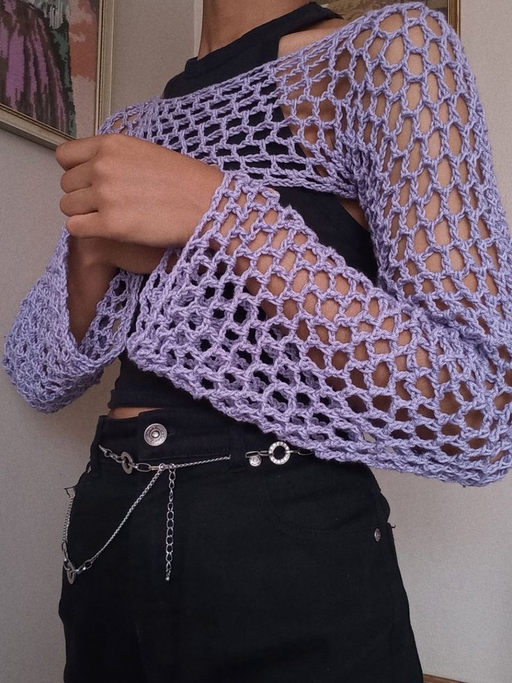 a woman is wearing a purple crochet sweater