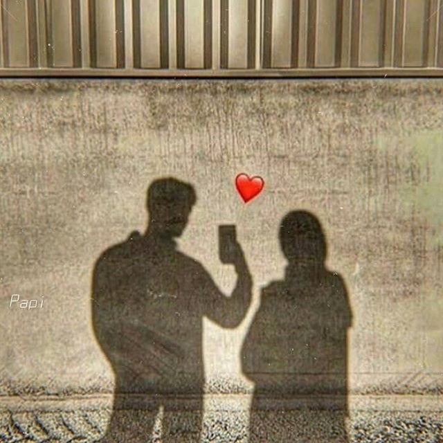 two people standing next to each other in front of a wall with a red heart