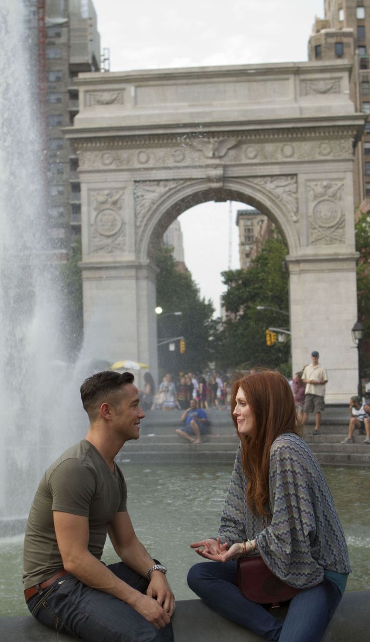 a man and woman sitting next to each other in front of a fountain