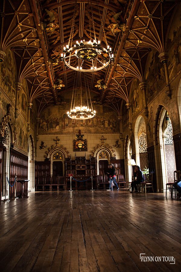 the inside of an old building with wooden floors and chandeliers hanging from the ceiling