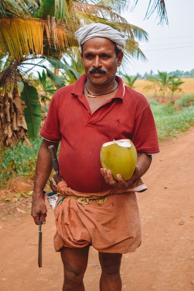 a man holding a coconut in his right hand and a knife in his other hand