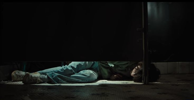 a man laying on the floor in front of a door with his head down and eyes closed