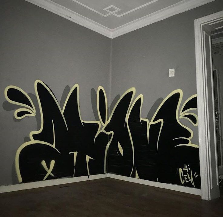 a wall with some graffiti on it in a room that is painted gray and black