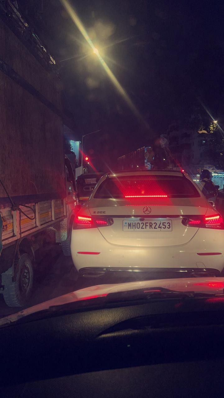 the back end of a white car on a city street at night