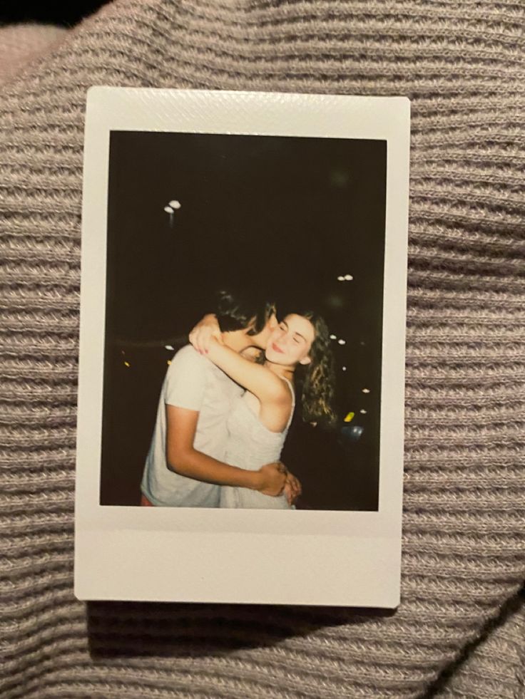 a polaroid photo of two people hugging each other on a sweater with bubbles in the background
