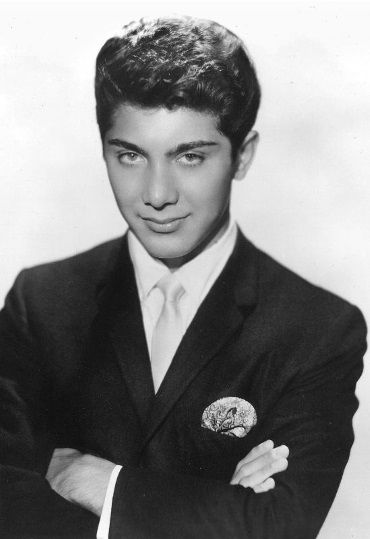 an old photo of a young man in a suit and tie with his arms crossed