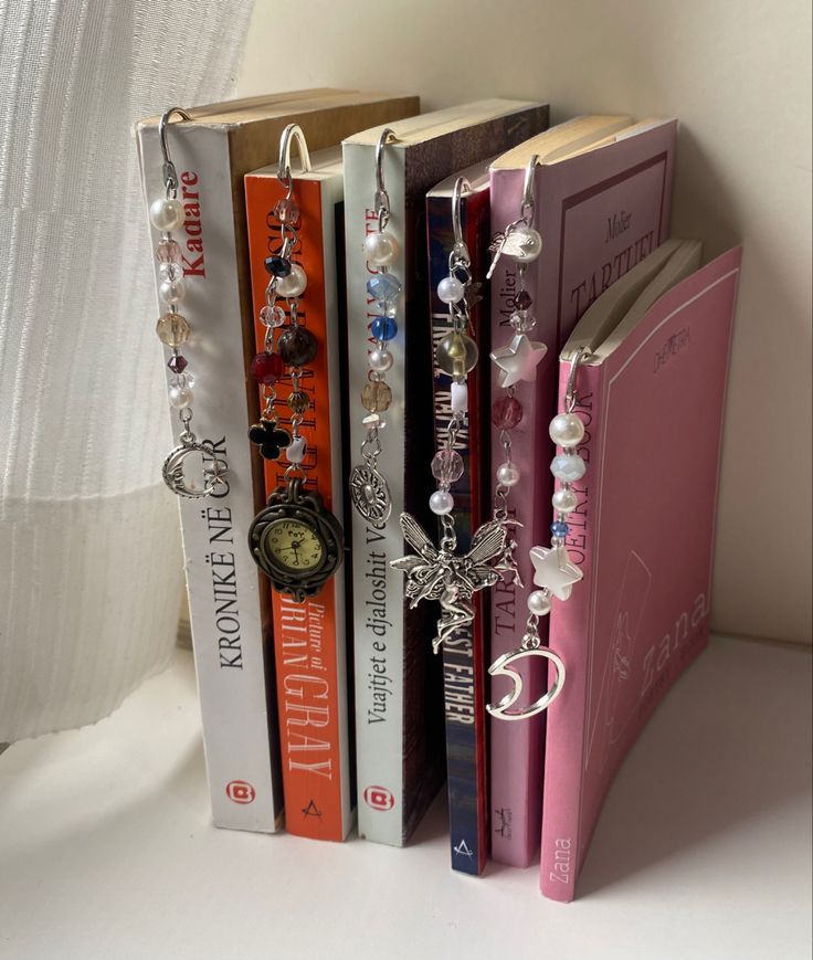 three bookends made out of books with beads and charms attached to the covers