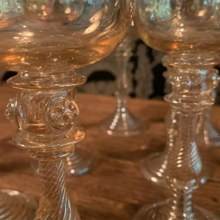 three clear glass goblets sitting on top of a wooden table next to each other