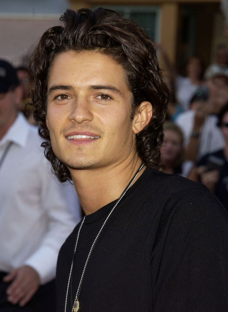 a young man with long hair standing in front of a crowd