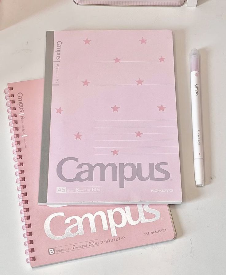 a pink notebook and pen sitting on top of a desk