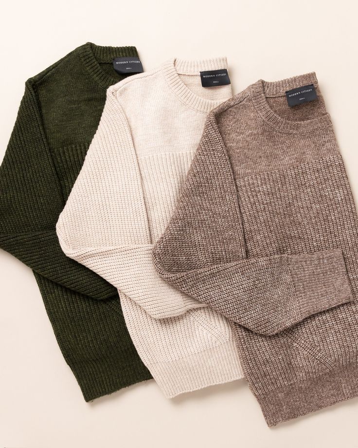 three sweaters sitting next to each other on a white surface