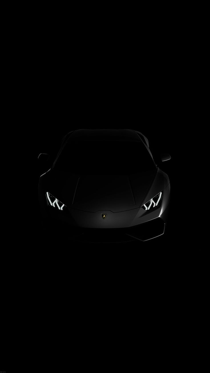 the front end of a black sports car in the dark with its headlights turned on