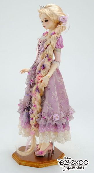 a doll with long blonde hair wearing a purple dress and flowered headdress