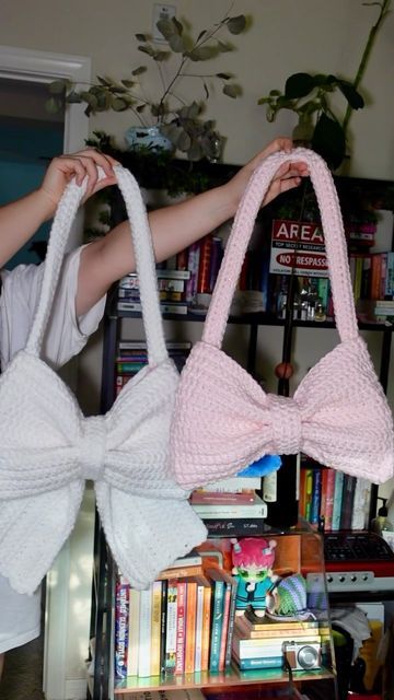 a woman holding two knitted bow bags