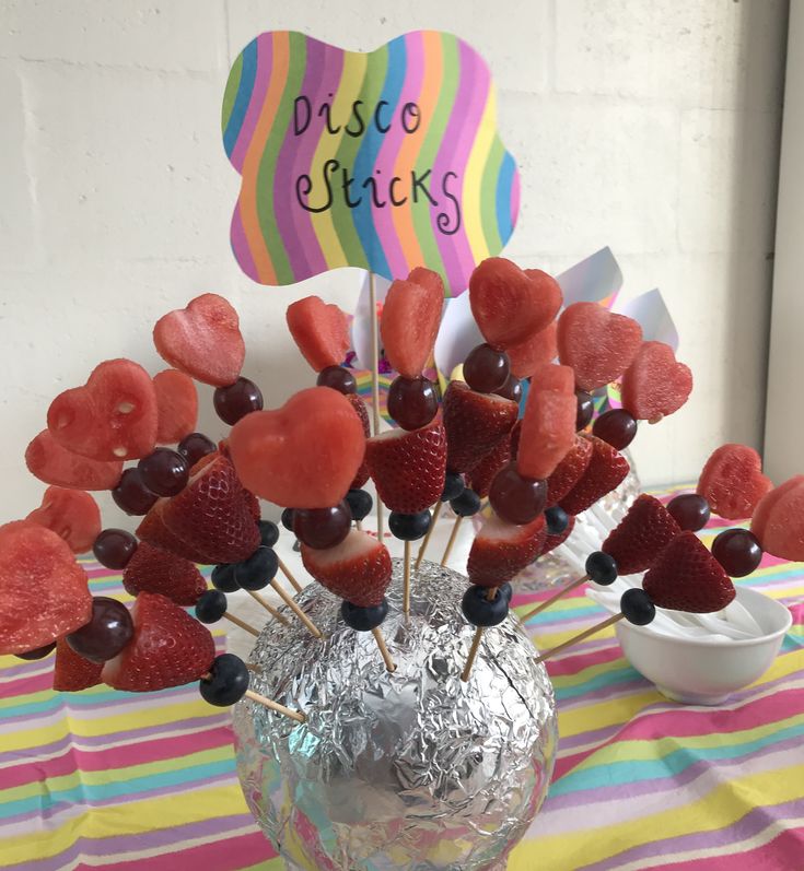 some strawberries and other fruit on sticks in a vase with a sign that says disco sticks