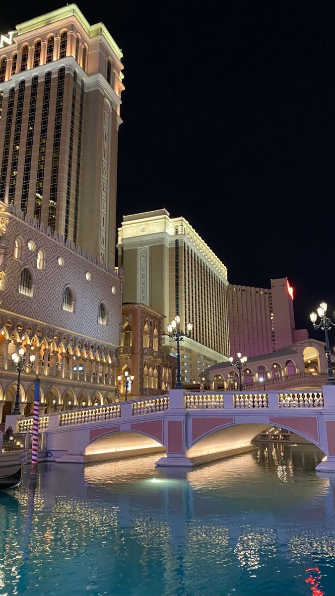 the las vegas hotel and casino is lit up at night with boats floating on the water