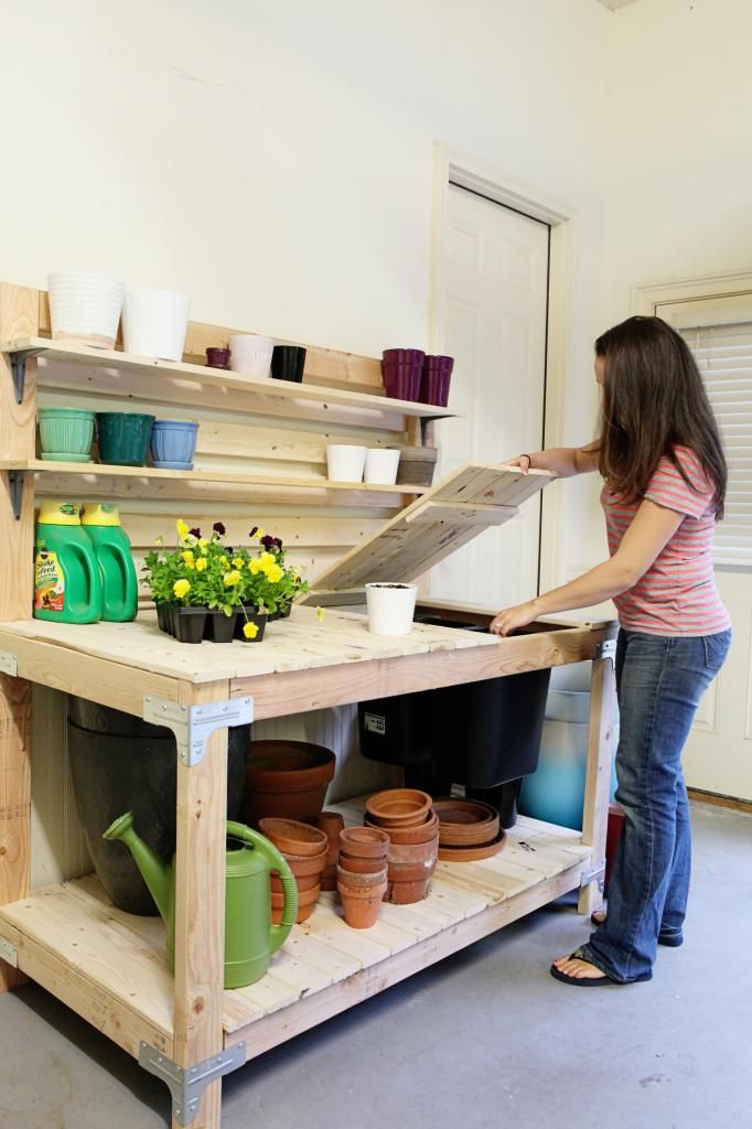 a woman standing next to a shelf filled with potted plants