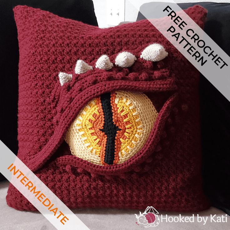 a crocheted pillow with an eyeball in the center and spikes on it