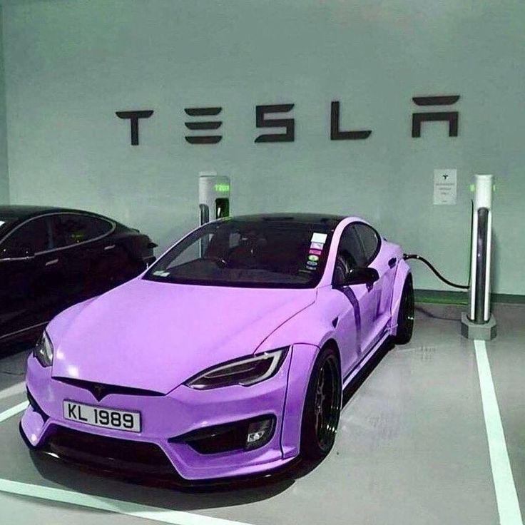 a purple car is plugged in to an electric charger at a tesla dealership