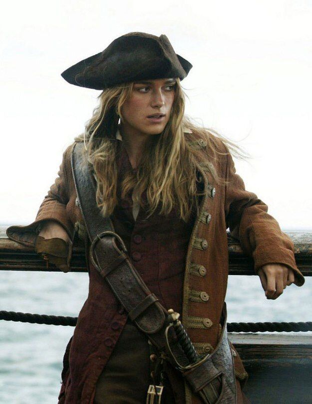 a woman dressed in pirate clothing standing on the deck of a ship
