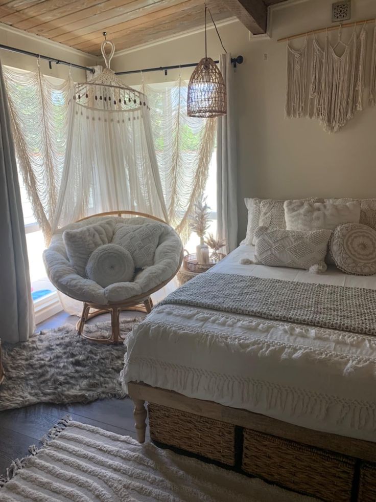 a white bed sitting next to a window in a bedroom under a wooden ceiling fan