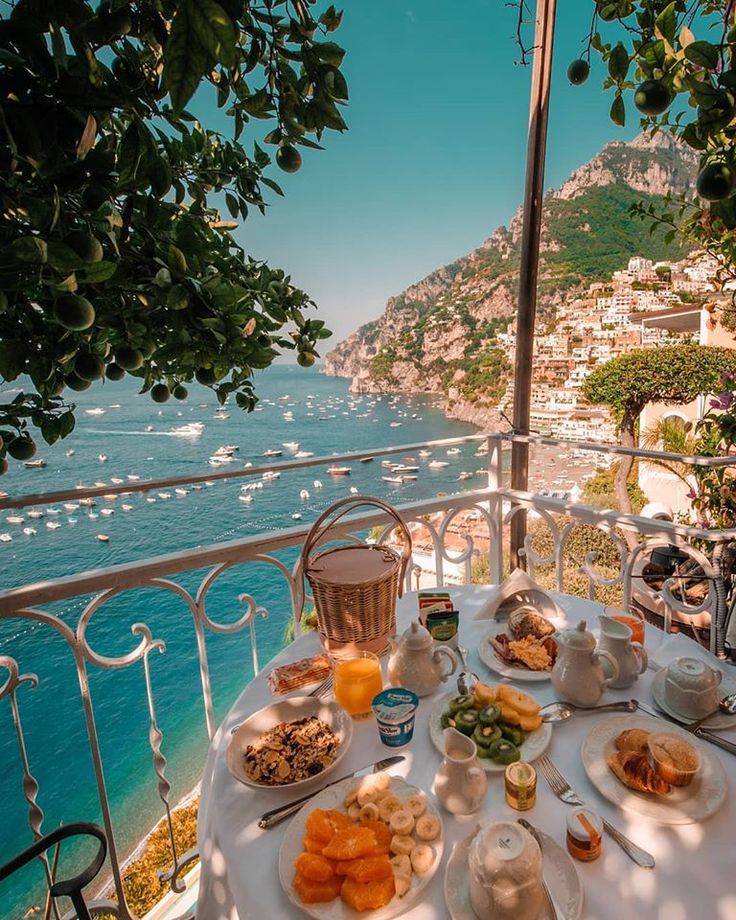 an outdoor table with food and drinks on it overlooking the ocean in positi, italy