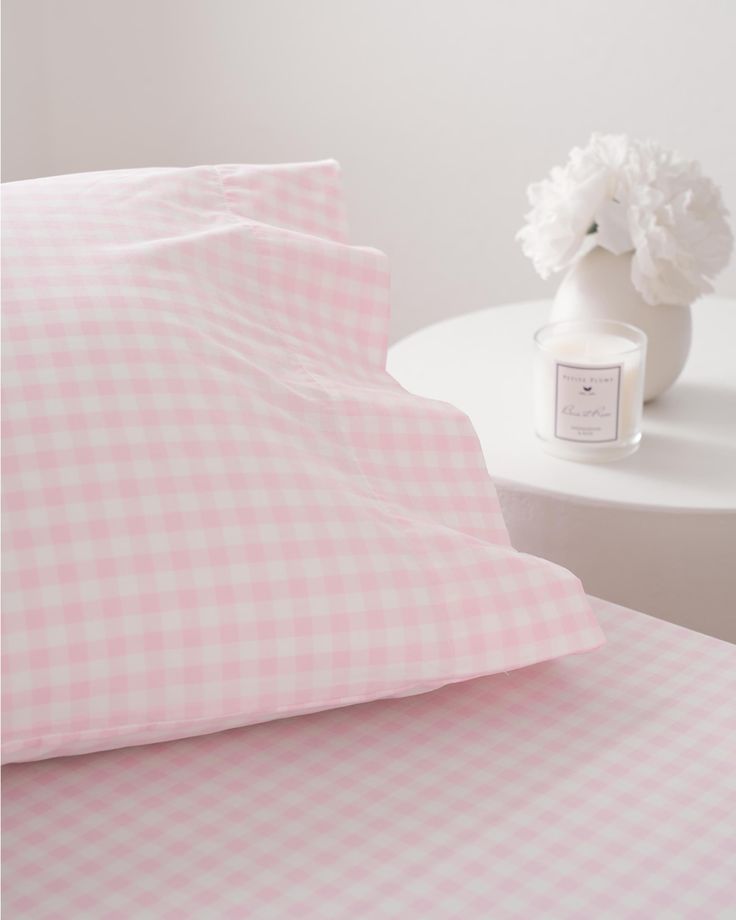 pink gingham bedding with white flowers on the side table in front of it