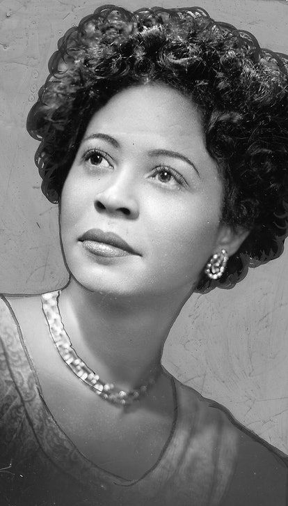 black and white photograph of a woman with curly hair wearing a necklace, looking off to the side