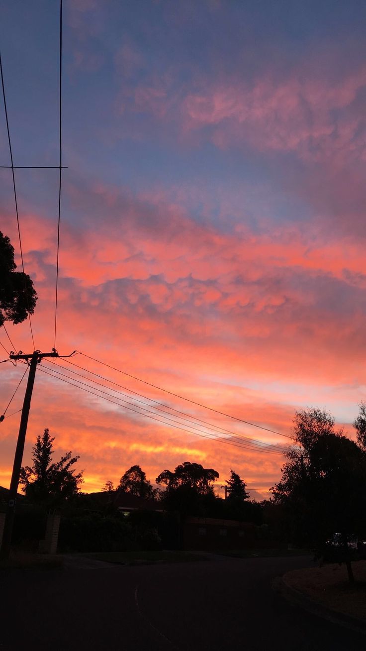 the sky is pink and blue as it sits on top of power lines at dusk