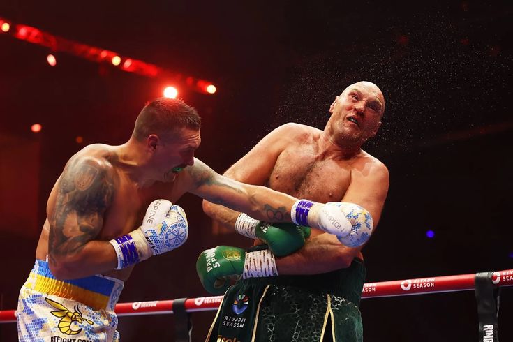 two men standing next to each other in a boxing ring with one man wearing green gloves