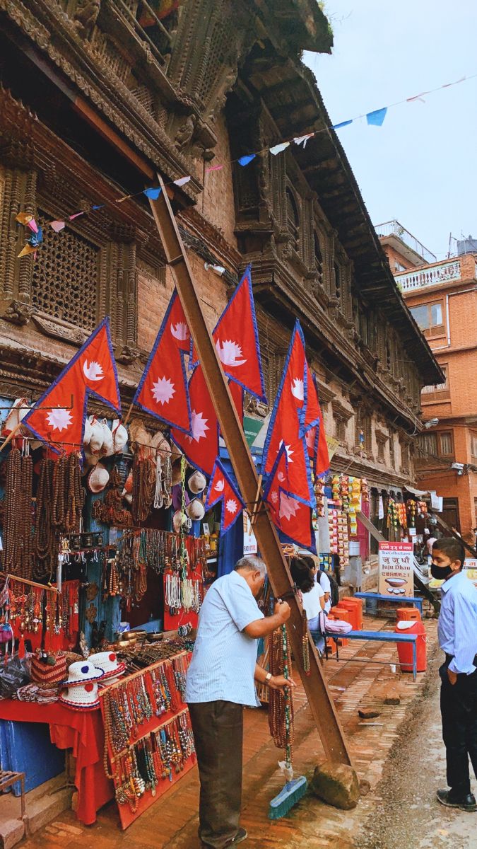 a man standing in front of a store with red and blue flags hanging from it's sides