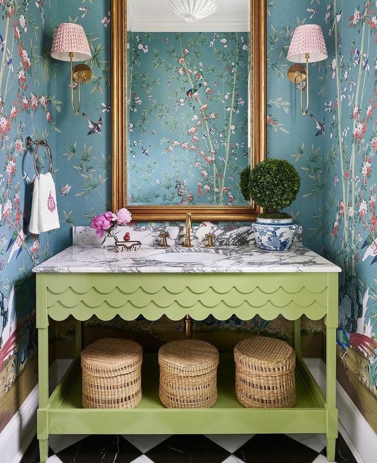 a green vanity with flowers on the wall next to a mirror and two wicker baskets