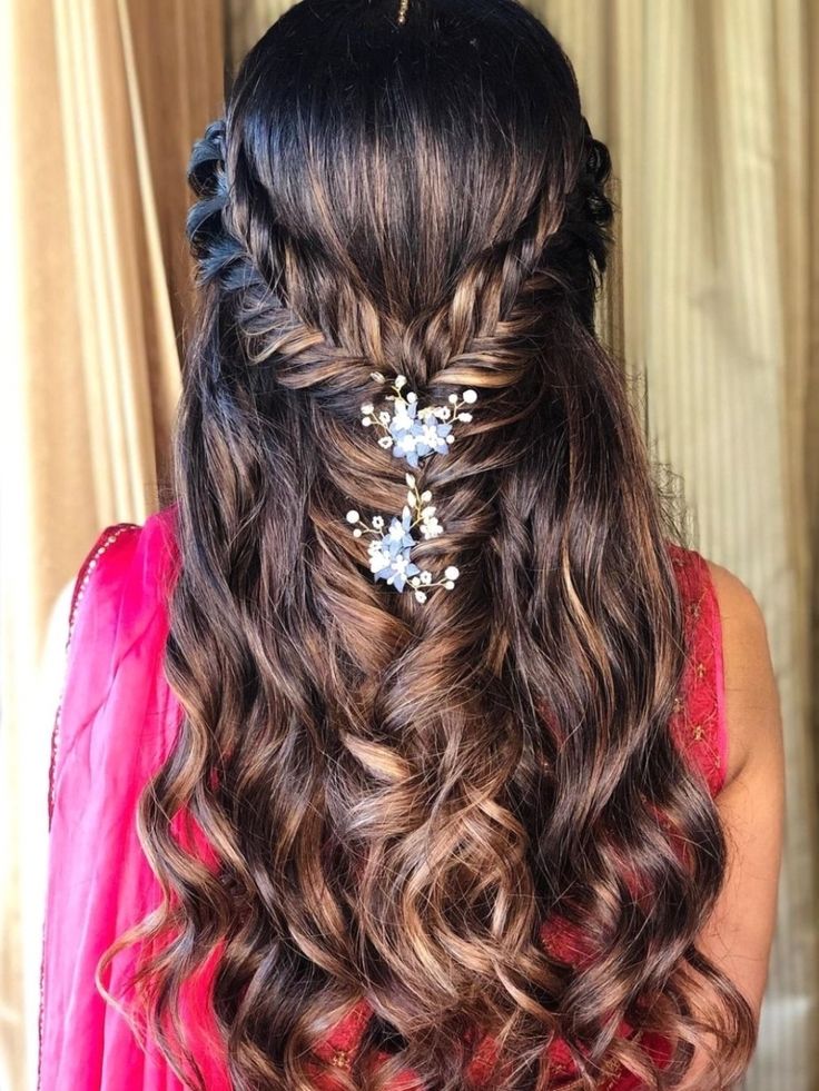 a woman with long wavy hair and flowers in her hair is shown from the back