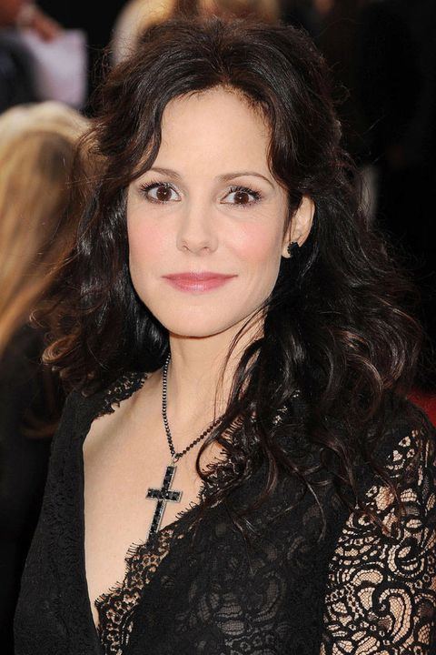 a woman with long hair wearing a black lace dress and cross necklace at an event