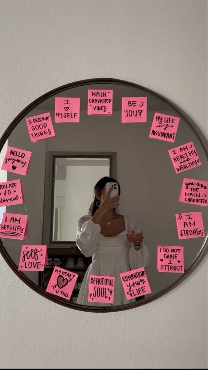 a woman taking a selfie in front of a mirror with sticky notes on it