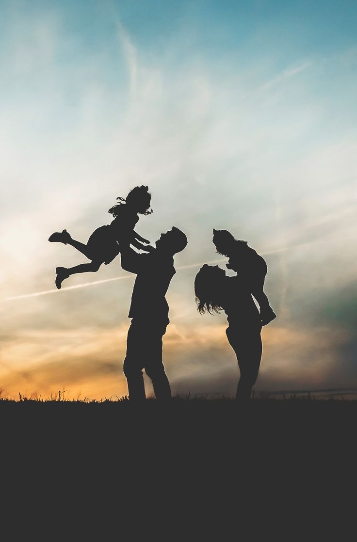 three people are silhouetted against an orange and blue sky