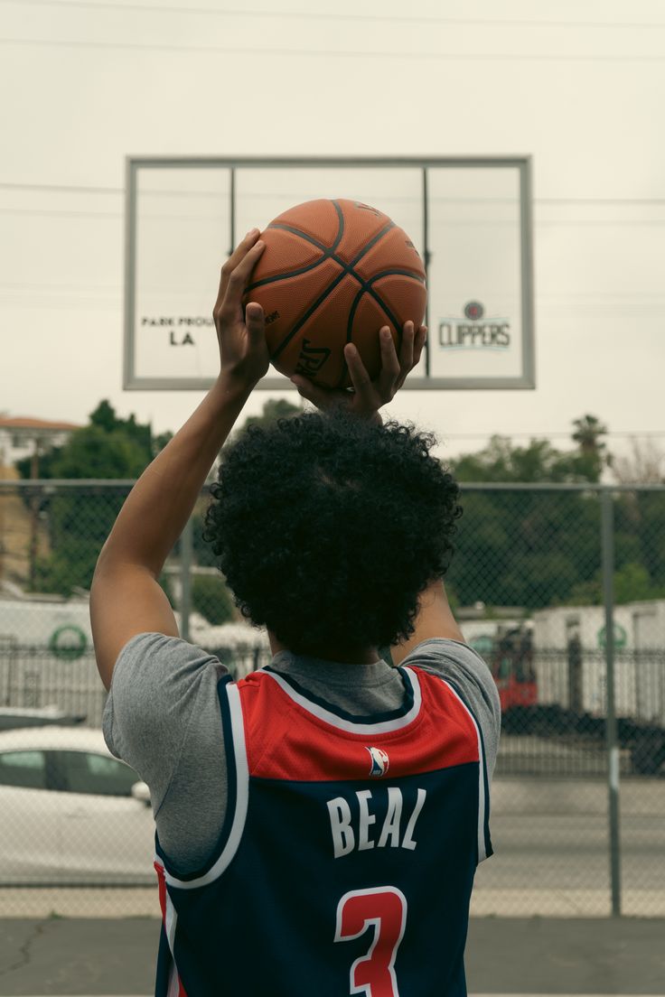 a young man holding a basketball up to his face