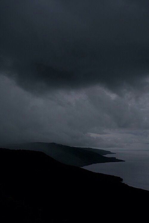 dark clouds hover over the ocean on a cloudy day